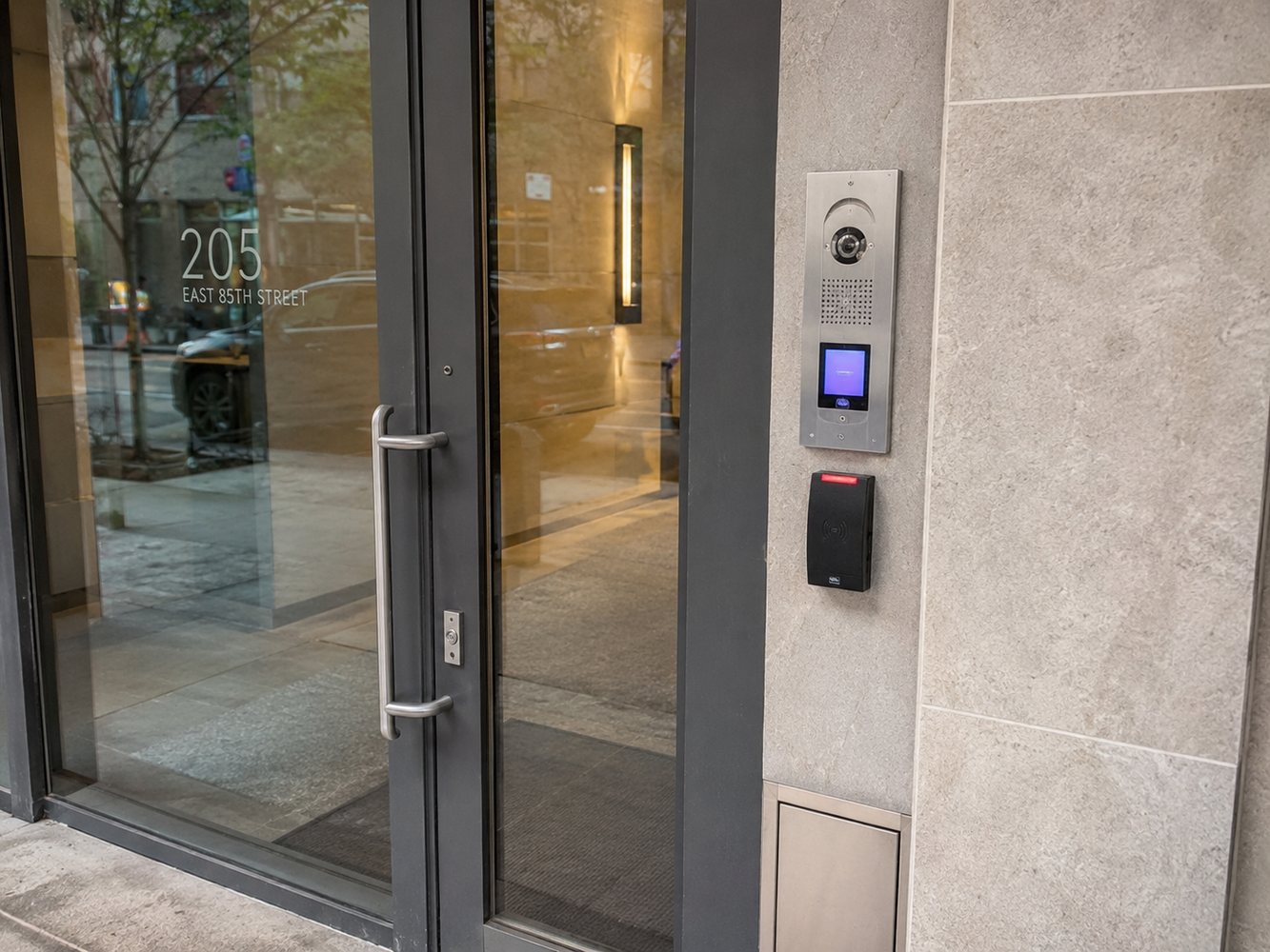 Building entrance access control reader installed beside a glass entry door