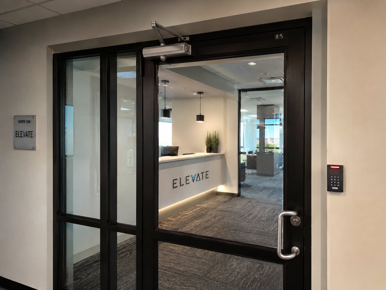 Keypad access control reader installed beside a glass office suite entry door