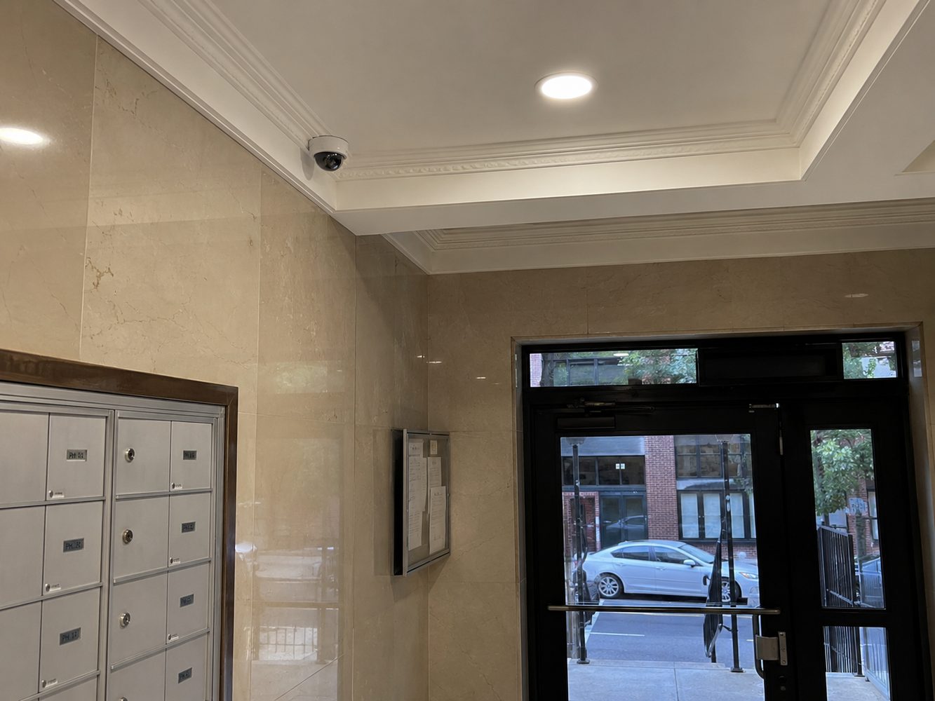 Dome security camera installed in an apartment building lobby near mailboxes and front entrance