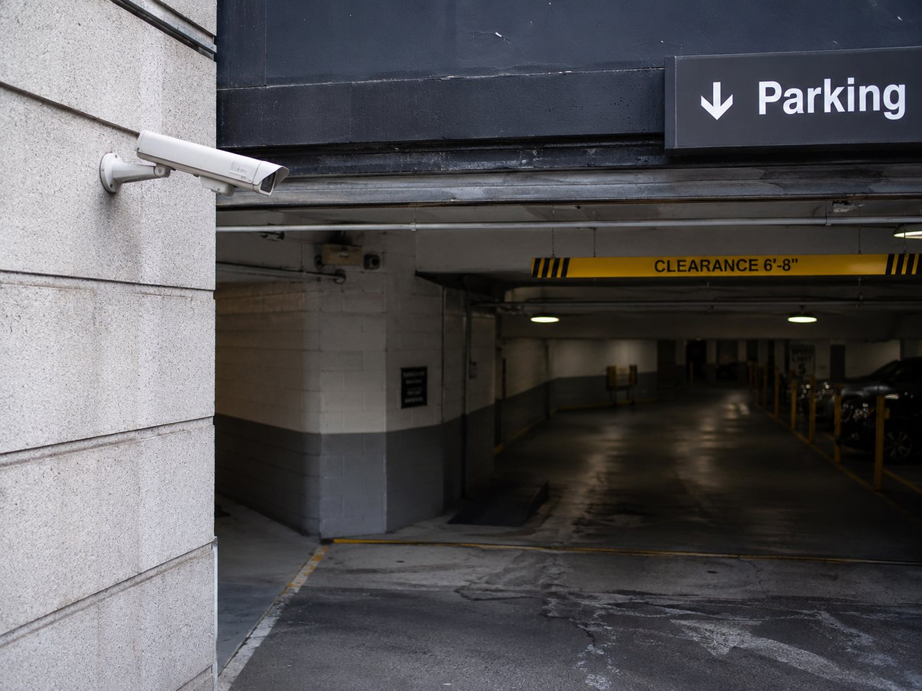 Exterior bullet security camera installed at a parking garage entrance for vehicle access surveillance